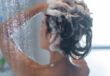 A lady shampooing her hair in the shower.