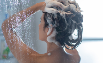 A lady shampooing her hair in the shower.